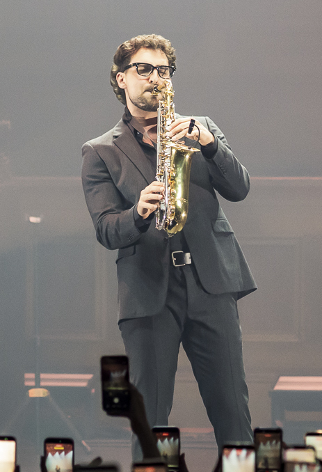 Saint Levant en concert, en costume sombre et lunettes, sur scène