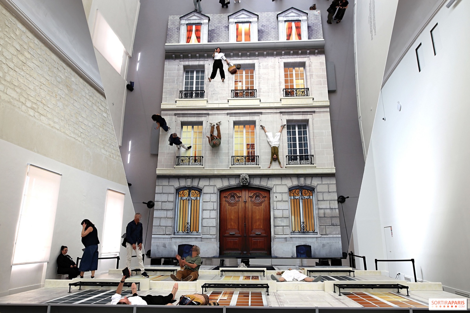 Installation Batiment de Leandro Erlich au Grand Palais : une facade d'immeuble haussmannien posee au sol, reflechie par un miroir incline, avec des visiteurs accroches aux balcons