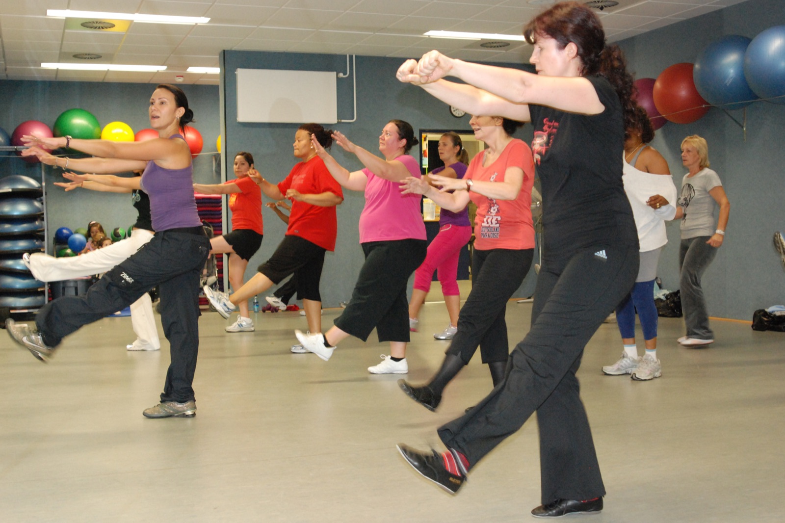 Cours de Zumba en salle, un groupe enchaîne une chorégraphie latine