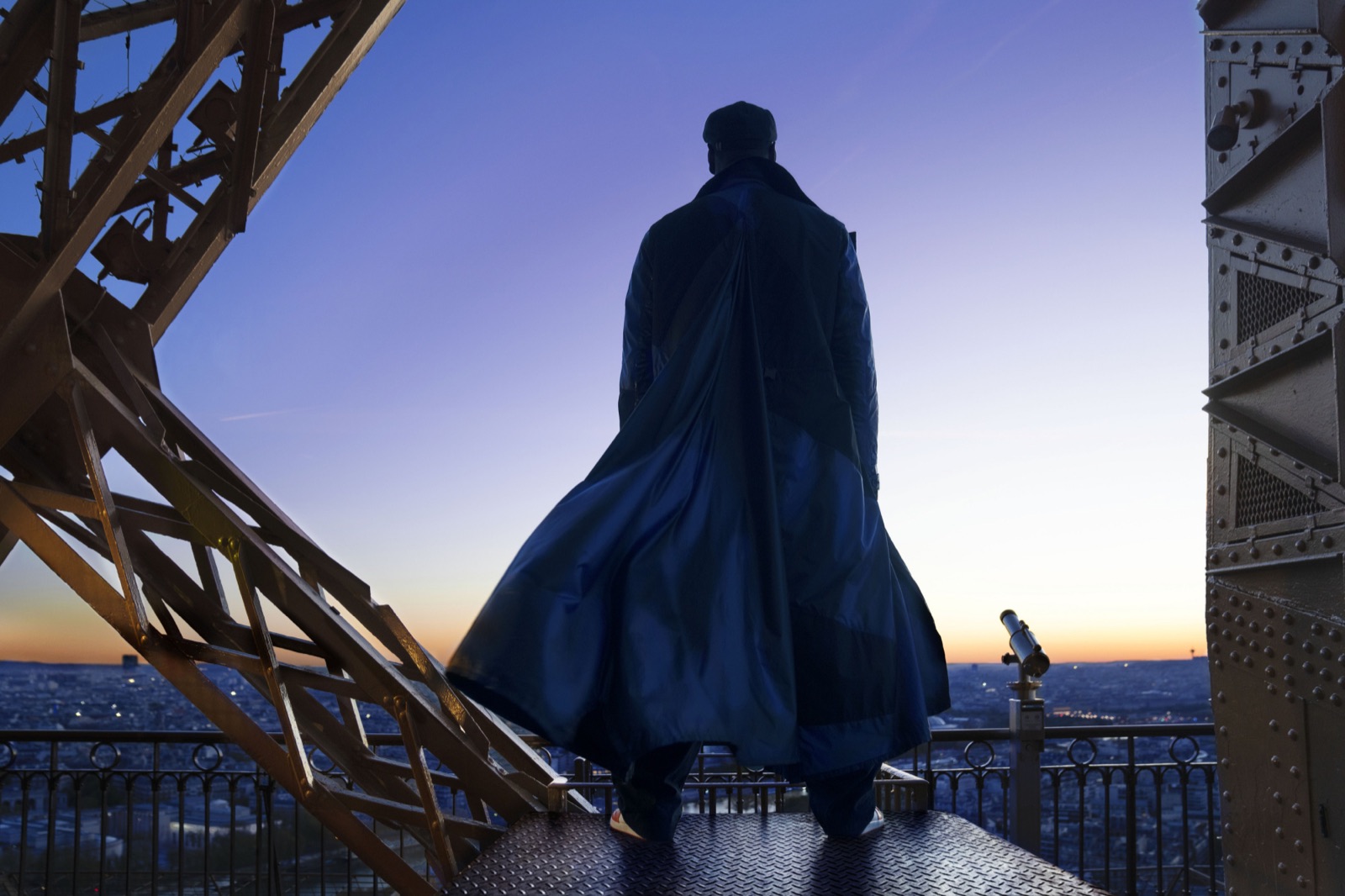 Silhouette d'Assane Diop en long manteau au sommet de la tour Eiffel au crépuscule, visuel officiel de Lupin partie 4 (Netflix)