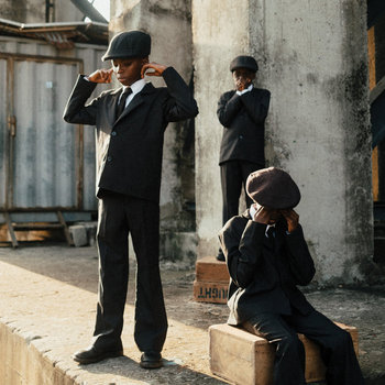 Pochette de l'album Here Because of Hope d'Ezra Collective : des enfants en costume et casquette dans une rue