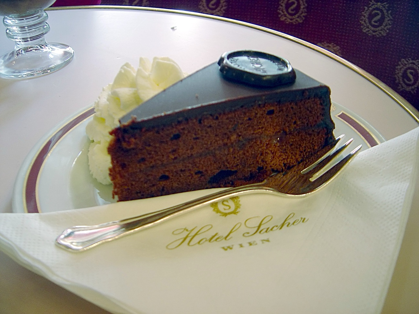 Part de Sachertorte nappée de chocolat avec crème fouettée sur une assiette de l'Hôtel Sacher à Vienne