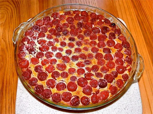 Clafoutis aux cerises doré dans un plat en verre, cerises rouges bien serrées