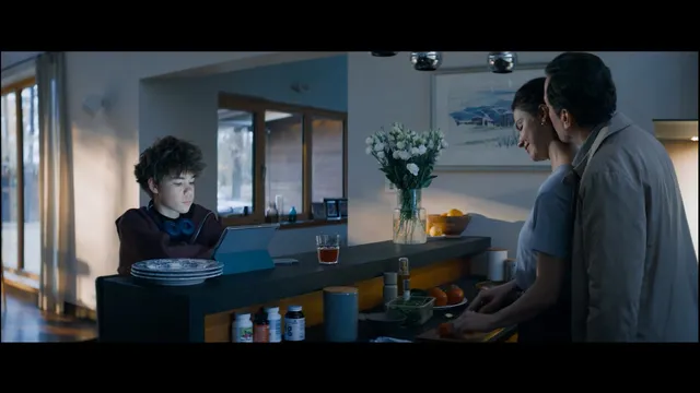 Scène du film Minotaure d'Andreï Zviaguintsev : une cuisine où un adolescent regarde une tablette pendant qu'un couple prépare le repas