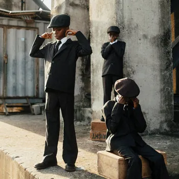 Pochette de l'album Here Because of Hope d'Ezra Collective : des enfants en costume et casquette dans une rue