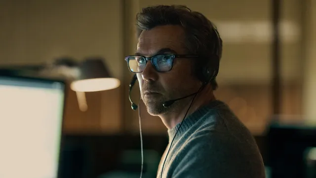 Ian Ridley, casque d'opérateur radio sur les oreilles, dans la pénombre d'un centre d'appels d'urgence dans la série Last Seen