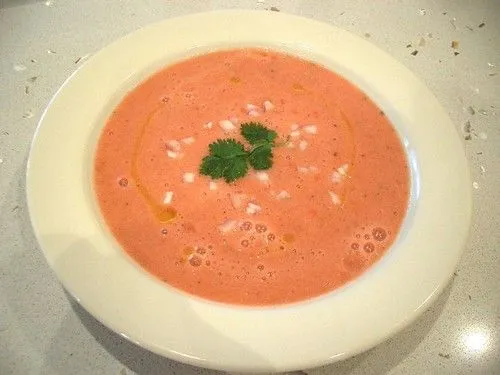 Assiette de gaspacho andalou rouge avec filet d'huile d'olive et brin de coriandre