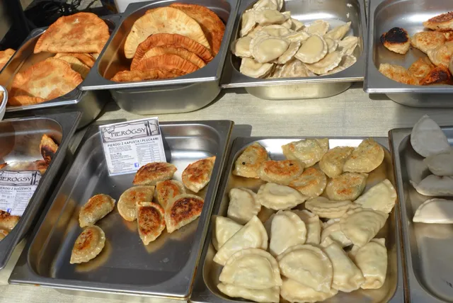 Plusieurs bacs de pierogi polonais, certains poêlés et dorés, d'autres pochés, présentés sur un étal