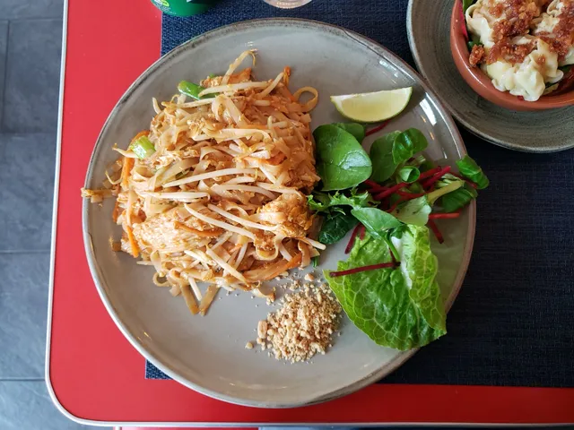 Assiette de pad thaï aux nouilles de riz, germes de soja, cacahuètes concassées et quartier de citron vert