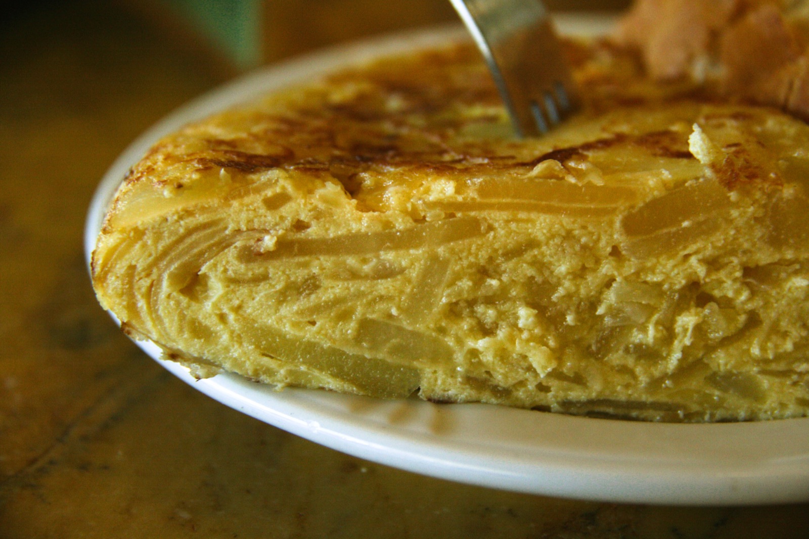 Coupe transversale d'une tortilla de patatas espagnole montrant les couches de pommes de terre, d'oignon et le coeur baveux